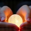 Two hands gently cupping a small, glowing orb, representing balance and harmony.
