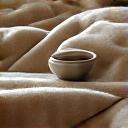 A warm, soft cashmere blanket with a steaming cup of tea, indicating comfort and coziness.
